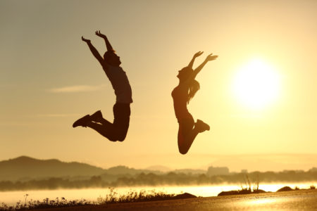 springendes glückliches Paar bei Sonnenuntergang