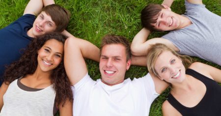 Jugendliche liegen zusammen auf einer Wiese