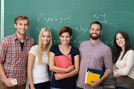 glückliche Schüler stehen in der Schule vor einer Tafel